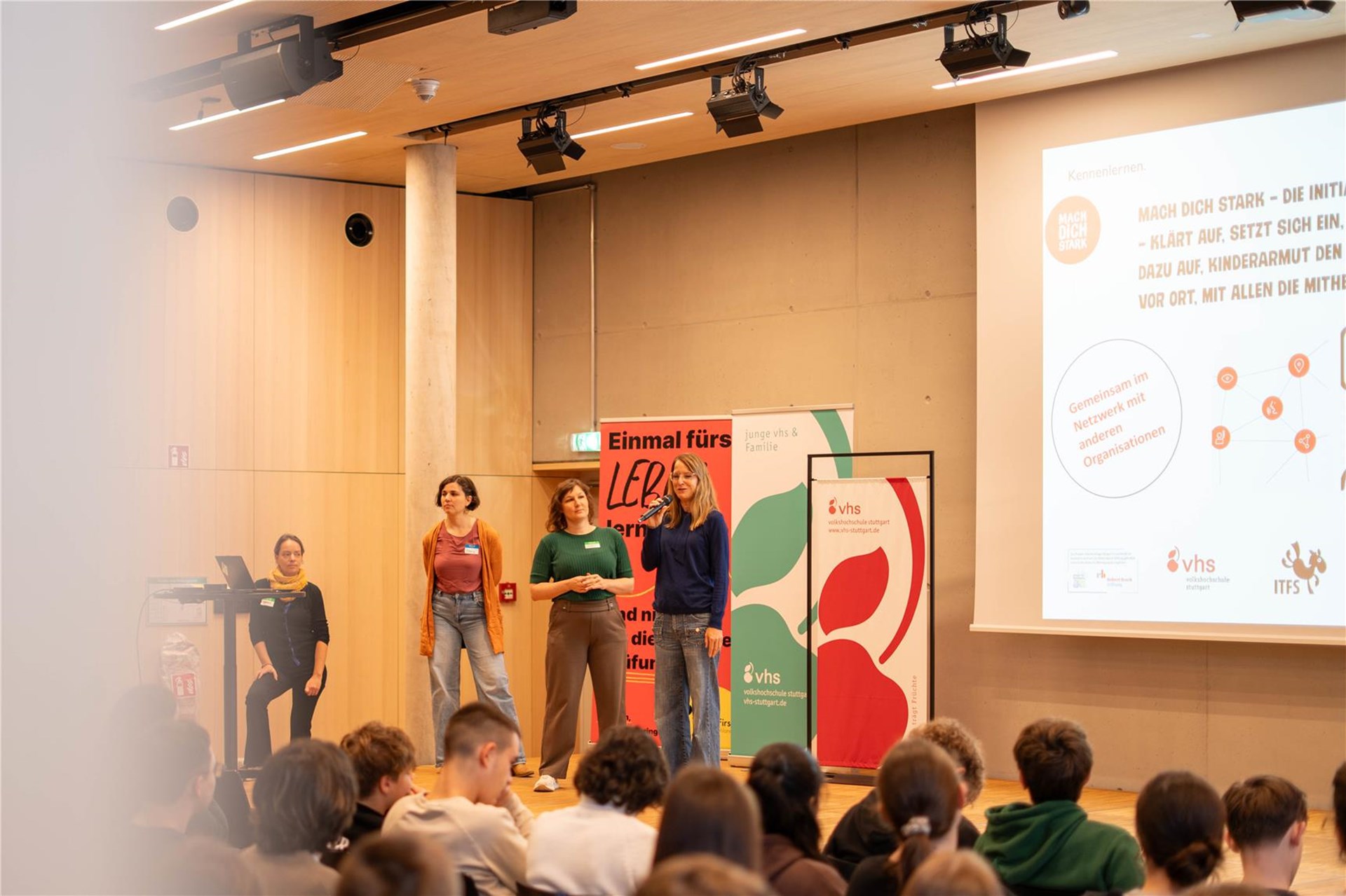 Personen auf einer Bühne vor einem Podium.