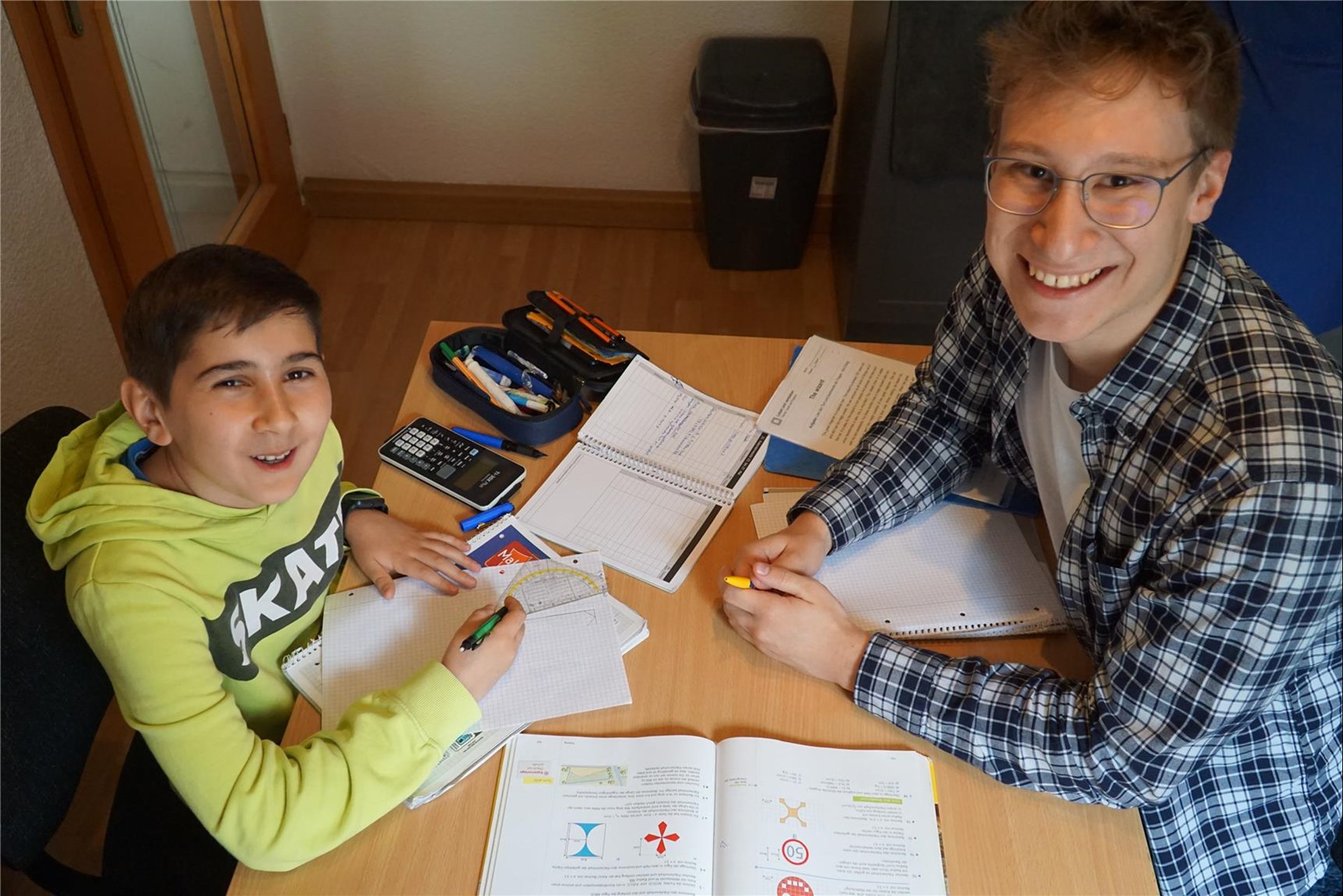 Schüler und Tutor lernen gemeinsam Mathematik am Schreibtisch.