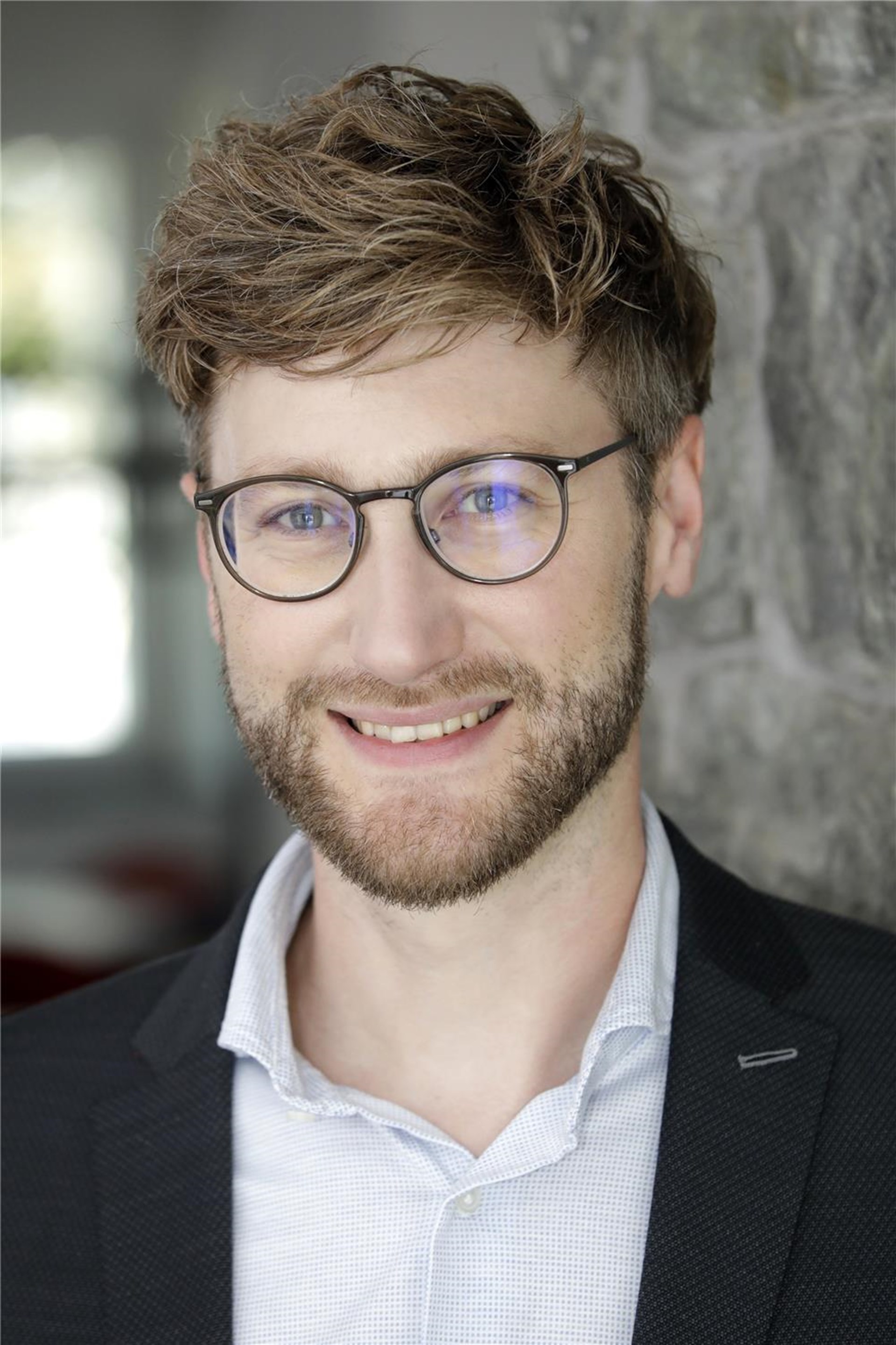 Junger Mann mit Brille lächelt in die Kamera